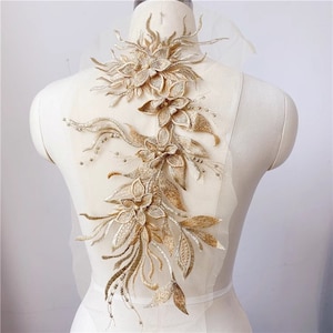 May include: Gold floral applique with delicate beading and intricate details. This embellishment is perfect for adding a touch of elegance to clothing, accessories, or home decor projects.
