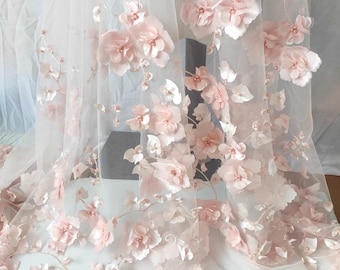 以下が含まれることがあります： 3Dのピンクの花と小さな真珠のようなアクセントで飾られた繊細なシアー生地。 花柄が生地全体に広がり、ロマンチックでエレガントな美しさを演出します。 ブライダルウェアや装飾プロジェクトに最適です。