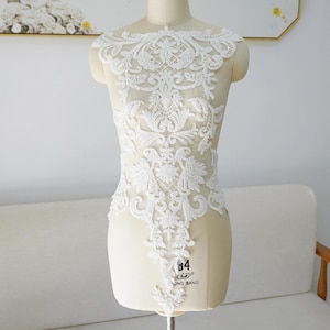 May include: White beaded lace applique with a floral design. The applique is approximately 38 cm tall and 25 cm wide.
