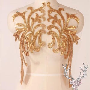 May include: Gold sequined applique with a floral design. The applique is on a sheer fabric background.