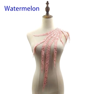 Puede incluir: Una aplicación de encaje rosa con un delicado diseño de plumas. La aplicación está adornada con pequeñas lentejuelas transparentes y es perfecta para añadir un toque de elegancia a la ropa o las manualidades.
