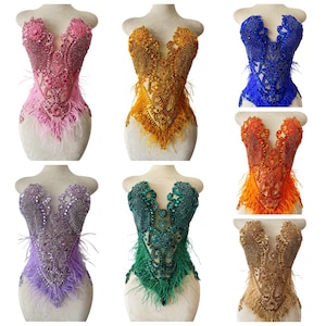 Puede incluir: Seis corpiños adornados en varios colores, incluyendo rosa, dorado, azul, naranja, morado, verde y beige. Cada corpiño presenta intrincados abalorios, lentejuelas y adornos de plumas. Los corpiños se exhiben en maniquíes.