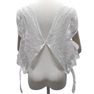 May include: White lace butterfly wings with a delicate design. The wings are attached to a white mannequin.