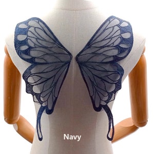 May include: A pair of navy blue butterfly wings made of sheer fabric with a delicate embroidered design. The wings are displayed on a white mannequin.