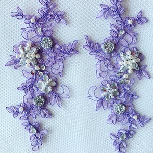 May include: Two purple lace appliques with pearl and rhinestone embellishments. The appliques are perfect for adding a touch of elegance to any project.