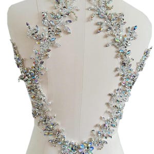 Könnte beinhalten: Ein Rückenstück aus Kristallverzierungen in Blumenform. Die Kristalle sind regenbogenfarben und haben eine silberne Rückseite. Die Verzierungen sind symmetrisch angeordnet.