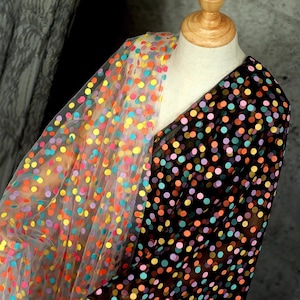 May include: Two pieces of sheer fabric with colorful polka dots. One piece is white with multi-colored dots and the other is black with multi-colored dots.
