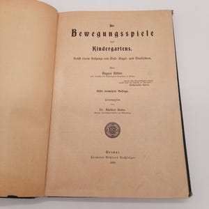 Könnte beinhalten: Ein Buch mit dem Titel "Die Bewegungsspiele des Kindergartens." von August Köbler, elfte Auflage, herausgegeben in Weimar von Hermann Böhlaus Nachfolger im Jahr 1899.