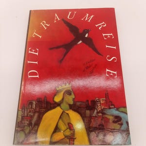 May include: A book titled "Die Traumreise" with a red cover. The cover features a black bird in flight and a stylized illustration of a person in a yellow cloak and crown, holding a red object. The book's title is in white, arched text.