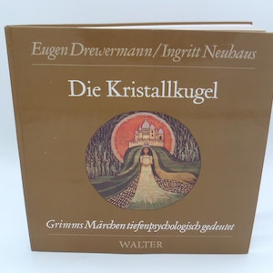 以下が含まれることがあります： 「Die Kristallkugel」というタイトルの茶色の本。著者はEugen DrewermannとIngritt Neubaus。表紙には、丘の上に白いドレスを着た女性が立っており、背景には城が描かれている。イラストの下には「Grimms Märchen tiefenpsychologisch gedeutet」というテキストが印刷されている。この本はWalterによって出版されている。