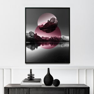 Può includere: Una fotografia in bianco e nero di una catena montuosa riflessa in un lago calmo. Le montagne sono parzialmente oscurate da due cerchi rosa sovrapposti.