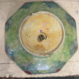 May include: Octagonal green and blue ceramic bowl with red accents. The bottom of the bowl has a white label with the text "Byzantia Ware" and "England".