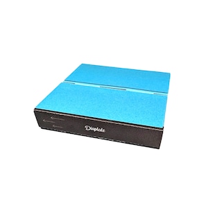 Peut inclure: Une boîte brune avec un dessus bleu et le mot "Displate" imprimé sur le devant. La boîte est fermée et des flèches pointent vers la droite.