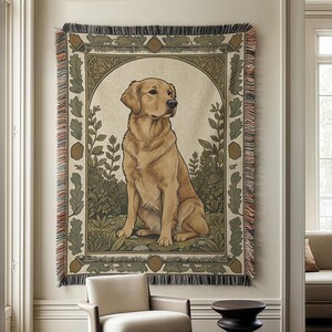 Puede incluir: Un gran tapiz con una ilustración de un perro golden retriever. La obra de arte está enmarcada por un borde decorativo con elementos botánicos en tonos verdes y marrones. El tapiz tiene un borde con flecos y está colgado en una pared.