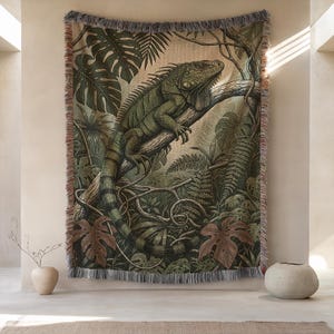 Puede incluir: Un tapiz tejido con una ilustración detallada de una iguana verde posada en una rama de árbol, rodeada de exuberante follaje tropical. El tapiz tiene un borde con flecos y un fondo neutro, creando una estética inspirada en la naturaleza.