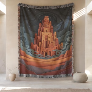 Op de afbeelding: Geweven sprei met een gestileerde illustratie van een kasteel tegen een donkerblauwe nachthemel. Het kasteel is in oranje en bruine tinten, met golvende lijnen op de voorgrond. De deken heeft een gefranjerde rand. Ongeveer 150 cm x 200 cm.