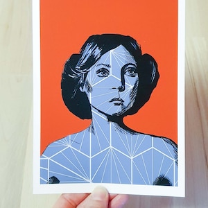 Könnte beinhalten: Ein blauer und weißer geometrischer Druck auf rotem Hintergrund. Der Druck zeigt das Gesicht einer Frau mit einem geometrischen Muster darüber.