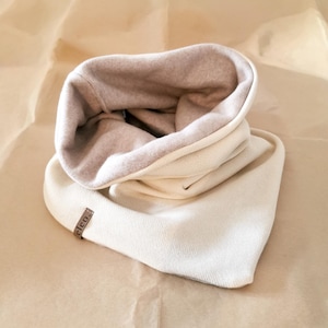 Fijn gebreide driehoekige lussjaal gevoerd met biologisch katoenen fleece.