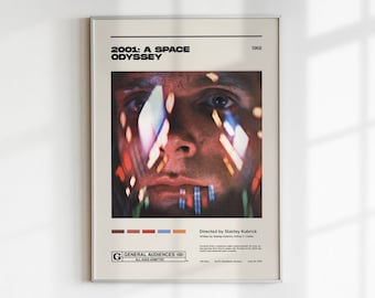 May include: A vintage movie poster for the film "2001: A Space Odyssey" featuring a close-up of an astronaut's face with a blurred background of lights. The poster is framed in a silver frame and has a G rating for general audiences.