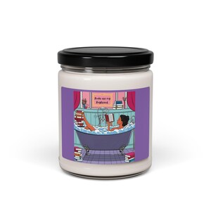 May include: A white candle jar with a purple background and a woman reading a book in a bathtub. The text on the jar reads "Books are my Boyfriend".