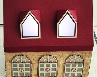 May include: A red and beige papercraft house with three windows and two dormer windows. The windows have a grid pattern and a candy cane design. The roof is red and the walls are beige.