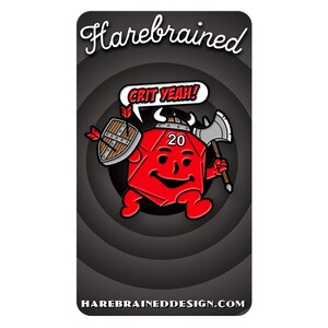 May include: A red 20-sided die with a smiling face, wearing a viking helmet and holding a shield and axe. The die is surrounded by a black and white circle with the text "CRIT YEAH!" and "HAREBRAINDEDDESIGN.COM".