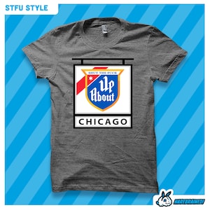 May include: Gray t-shirt with a graphic of a sign that says "Shut the Fuck Up About Chicago". The sign is in the style of a vintage beer sign.