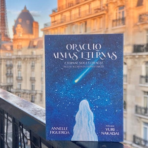 May include: A blue and white oracle deck called "Oraculo Almas Eternas" or "Eternal Souls Oracle" with 36 cards in Spanish and English. The deck features a starry night sky with a shooting star and a figure in a white robe.