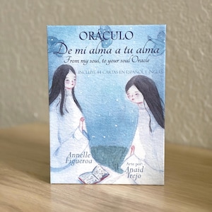 Peut inclure: Une boîte de jeu de cartes oracle rectangulaire avec une illustration aquarelle bleue de deux personnages en robes blanches. Le texte indique ORÁCULO De mi alma a tu alma From my soul, to your soul Oracle INCLUYE 44 CARTAS EN ESPAÑOL E INGLÉS Annelle Figueroa Arte por Anaid Trejo.