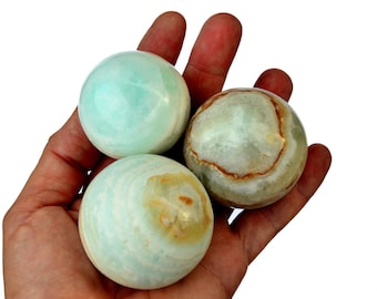 May include: Three smooth, polished spheres of green and brown onyx. The spheres are about the size of a golf ball and have a swirling pattern.