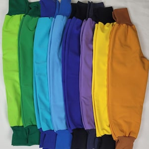 May include: A set of ten colorful pants with elastic waistbands and cuffs. The pants are arranged in a rainbow order, starting with green and ending with orange.