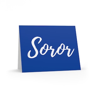 May include: A blue card with the word "Soror" written in white cursive script.