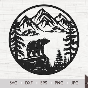 May include: Black and white silhouette of a bear standing on a rock in front of a mountain range with pine trees on either side. The image is in a circle.