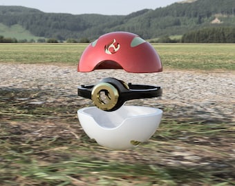 Op de afbeelding: Een rood en wit Poke Ball speelgoed met een gouden ring en een zwarte basis. De bovenkant van de Poke Ball is open, waardoor de binnenkant van het speelgoed zichtbaar is.