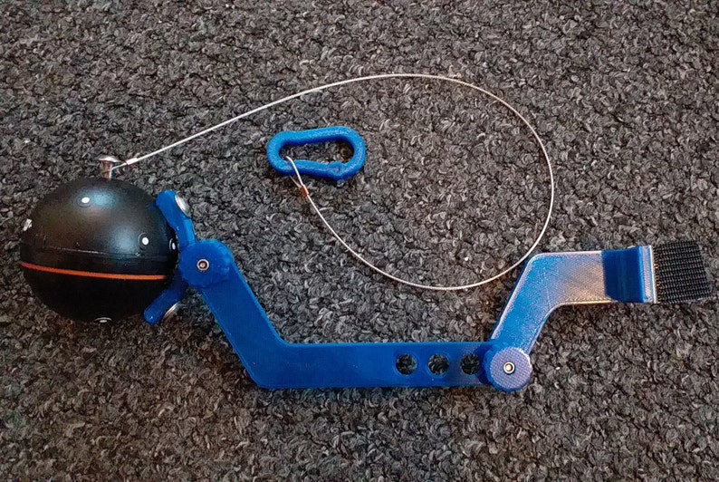 May include: A blue plastic tool with a black sphere attached to one end. The tool has a hook on the other end and a string attached to the sphere. The tool is designed for retrieving objects from hard-to-reach places.