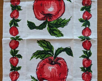 May include: A white kitchen towel with a repeating pattern of red apples and green leaves. The apples are depicted whole and sliced, with a vintage, hand-drawn style. The towel has a classic, farmhouse aesthetic.