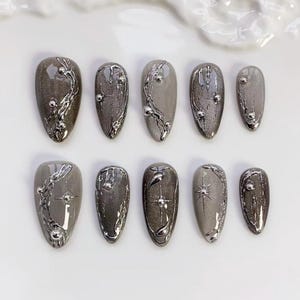 May include: A white ceramic mug with a black handle and the text "But First, Coffee" in a bold, black font. The mug is set against a blurred background, suggesting a cozy setting.