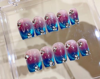 Peut inclure: Ensemble de dix faux ongles avec un dégradé de rose à bleu et des strass.
