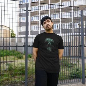 May include: Black t-shirt with a green skull graphic. The skull design is intricately detailed, created with a dotted texture. The t-shirt is a standard crew neck, ideal for everyday wear.