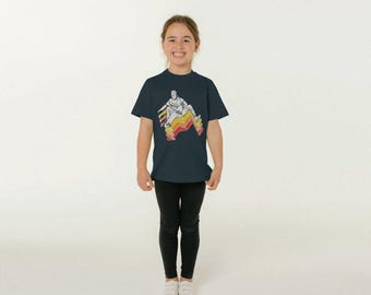 May include: A navy blue t-shirt featuring a retro-style graphic of a person jumping over a colorful, striped design in shades of yellow, orange, and red. The shirt is worn by a young person, paired with black leggings and white sneakers.