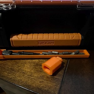 May include: An orange RIDGID toolbox with a matching handle and a tray of bits. A separate orange piece sits in front of the tray. The toolbox is black and has a clear top. The handle and tray are orange.