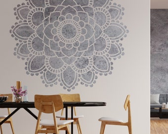 May include: A white wall with a large gray mandala stencil design. A black table with four wooden chairs is in front of the wall.