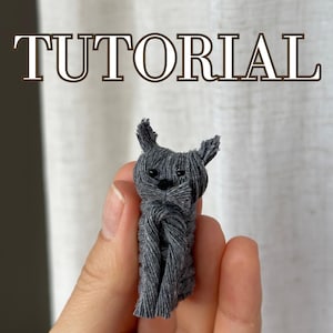 Peut inclure: Une figurine de chat en laine grise, un projet de bricolage, avec le mot "TUTORIAL" en texte brun au-dessus.