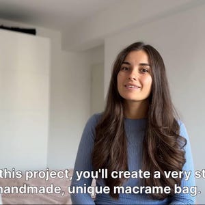May include: A woman with long brown hair is smiling and looking at the camera. She is wearing a light blue sweater. The text "Using this project, you'll create a very stylish, handmade, unique macrame bag." is visible at the bottom of the image.