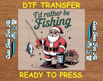 May include: A DTF transfer design featuring Santa Claus fishing. Santa is wearing a red suit, sunglasses, and a Santa hat. The text reads "I'd rather be Fishing" and "Ready to Press". The design includes a fish, a bucket, and a small sled with gifts.
