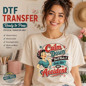 May include: A cream-colored t-shirt featuring a graphic of a retro-style woman with dark hair and a red headband. The text reads: Calm Down We'll Make it look like an Accident. The design includes red, teal, and black colors with star accents.