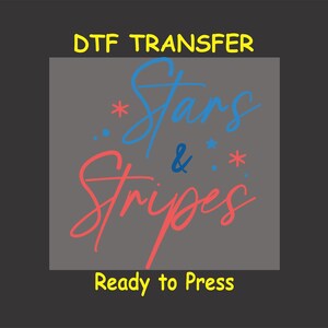 May include: A gray background with the text "DTG Transfer" in yellow at the top. The text "Stars & Stripes" is written in a handwritten style in blue and red. The text "Ready to Press" is in yellow at the bottom.