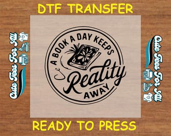 May include: A black and white design on a clear sheet, ready to be pressed. The design features a book with the text "A book a day keeps reality away".