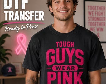 May include: A black short-sleeved t-shirt featuring the bold pink text TOUGH GUYS WEAR PINK with a small pink ribbon icon at the bottom. The design is printed on the front of the shirt, which is worn by a person in a casual setting.