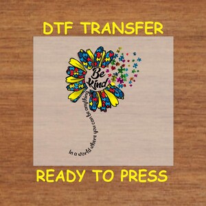 May include: A DTF transfer design featuring a yellow sunflower with puzzle pieces forming the petals. The center of the flower has the words "Be Kind" and a text swirl around the flower that reads "In a world where you can be anything."
